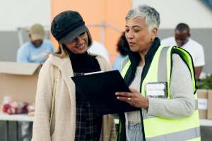 Pictured: Two women look at a clipboard together while two men work in the background